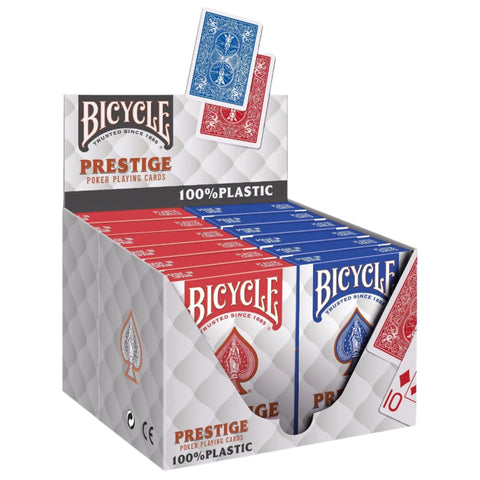 A display box containing 12 decks of Bicycle Prestige 100% Plastic Poker Playing Cards, with individual packs visible in red and blue colors.